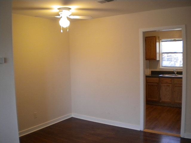 an empty living room with a ceiling fan